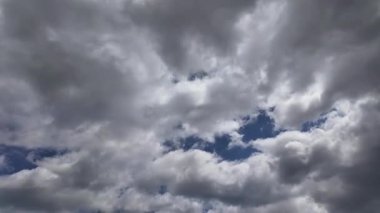 Beyaz bulutların açık mavi gökyüzünde sürüklendiğini gösteren hızlandırılmış video. Huzurlu ve doğal bir atmosfer..