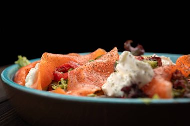 Taze ve canlı salata taze somon, yapraklı yeşillikler ve yumuşak krem peynir karışımı.