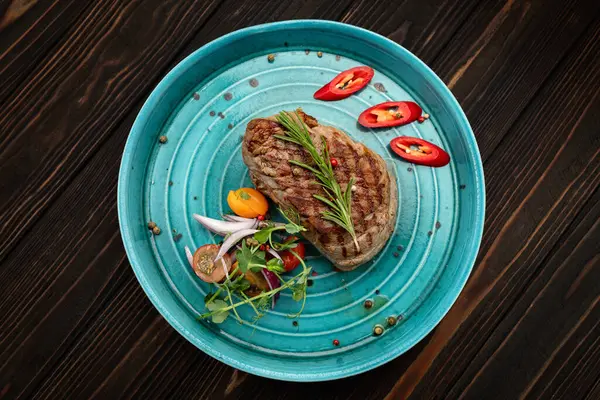 Renkli taze sebzelerle servis edilen sulu ızgara biftek.