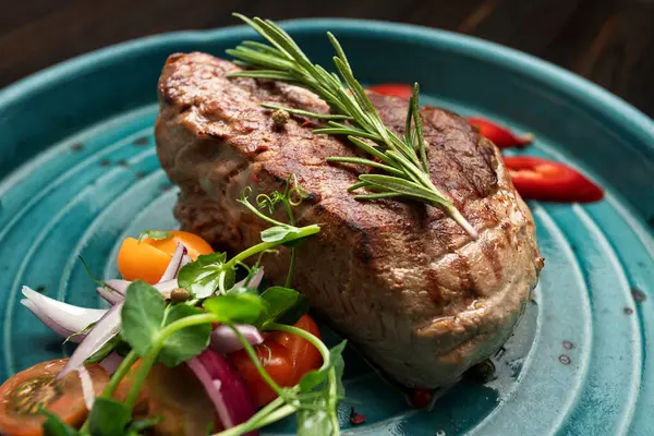 Renkli taze sebzelerle servis edilen sulu ızgara biftek.