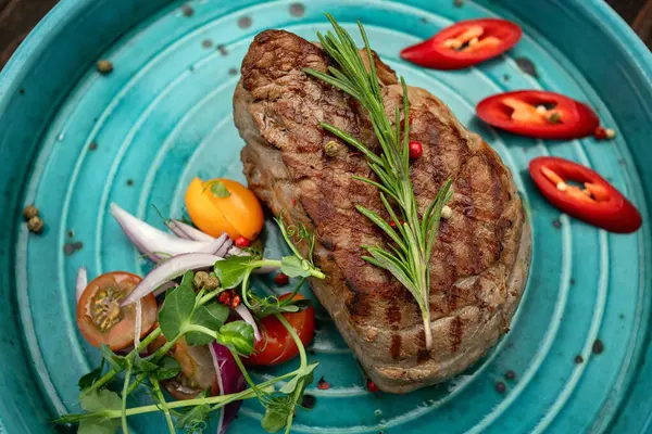 Renkli taze sebzelerle servis edilen sulu ızgara biftek.