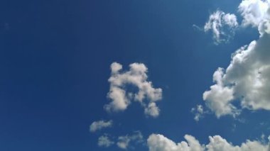 Beyaz bulutların güzel zamanlaması açık mavi gökyüzünde yavaşça hareket ediyor. Metin için alanı olan minimal arkaplan. Doğa, çevre ve iklim temaları için ideal.