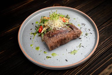 Kızarmış sebze ve aromalı sosla servis edilen sulu ızgara biftek. Restoran menüleri, yemek kitapları, reklamlar ve yemek dağıtım hizmetleri için çok kaliteli bir sunum..