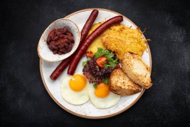Bir tabakta kızarmış sosis, yumurta, tost, domates, fasulye ve yeşillik ile doyurucu bir kahvaltı..