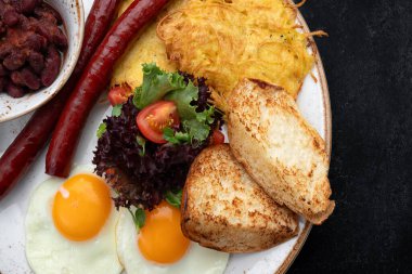Bir tabakta kızarmış sosis, yumurta, tost, domates, fasulye ve yeşillik ile doyurucu bir kahvaltı..