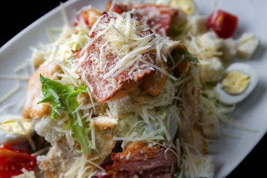 Marul, tavuk, kızarmış ekmek, parmesan peyniri ve soslu taze Sezar salatası, sığ bir tarla derinliğinde yakalanır..