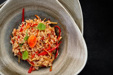 Delicious risotto with vegetables on plate, gourmet italian cuisine on dark background.