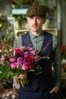 Kadınlar Günü ya da Sevgililer Günü konsepti. Tepeli şapkalı çekici bir erkek ve 20 'li yaşlarda güzel kırmızı ve menekşe çiçekleri tutan klasik kıyafetler. Çiçeklerle tebrik ediyorum. Yüksek kaliteli resim