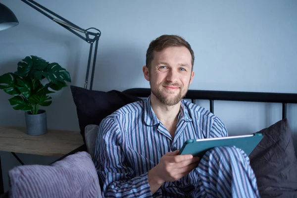 Młody Pogodny Człowiek Korzystający Tabletu Siedzący Rano Łóżku Robiący Zakupy — Zdjęcie stockowe