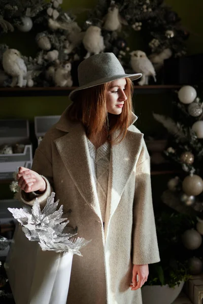 アウターで魅力的な白人スタイリッシュな女の子とコンセプトストアやスーパーマーケット内のクリスマスの装飾で立って帽子 新年2023ショッピング装飾や消費者主義 Masショッピングコンセプト — ストック写真