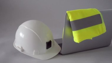 İnşaat, tasarım, mimari veya inşaat endüstrisi iş yeri konsepti. Beyaz güvenlik kaskı, yansıtıcı yelek ve bilgisayar mühendislerin masasında. Yüksek kalite 4k video kaydı