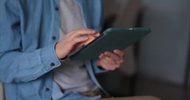 Yakındaki erkek tablet bilgisayarda çalışıyor ya da eğitim görüyor. Dijital tablet kullanarak kot gömlek giyen serbest çalışan bir adam. Çevrimiçi alışveriş, gezinme, çevrimiçi mağaza veya e-ticaret konsepti. 4k video