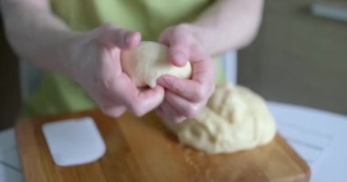 Yeşil önlüklü erkek aşçı arka planda ahşap kesim tahtasıyla hamur topları yapıyor. Ev yapımı mutfak konsepti, ev yapımı pişirme. Yüksek kalite 4k video kaydı