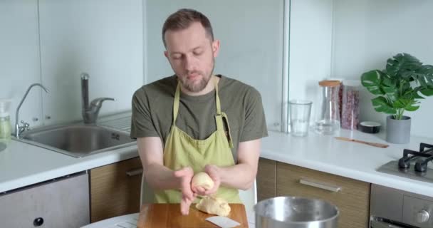 초록색 앞치마를 쾌활하게 감독자는 도마를 배경으로 덩어리를 만든다 주방에서 일하고 — 비디오