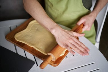 Paskalya pastası konsepti. Beyaz aşçı erkek fırıncı yeşil önlüklü. Mutfakta hamur yoğurmak için merdaneyi kullanıyor. Yüksek kaliteli resim