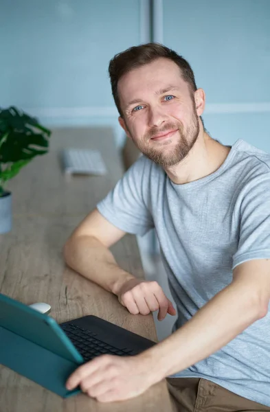 魅力的な白人男性のフリーランスや起業家の概念 自宅のオフィスに座ってビジネスのためのタブレットコンピュータを使用して成功したひげそりの男 高品質垂直写真 ストック写真