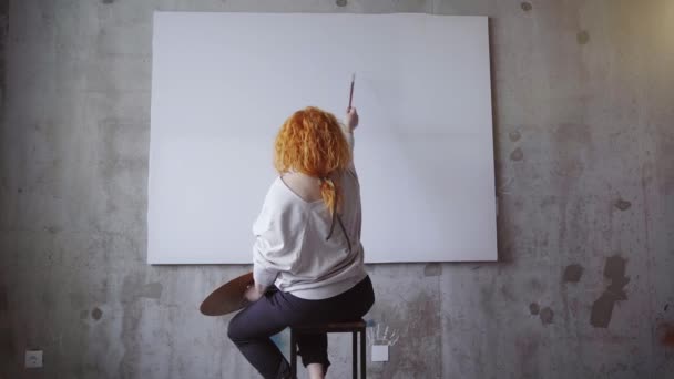 Cheerful Redhead Artist Woman Sitting Front White Blank Canvas Concrete — 비디오