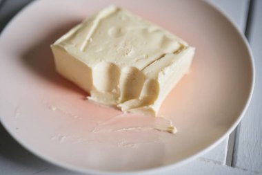 Fresh soft butter for a morning sandwich. Piece of butter on plate in kitchen. High quality photo