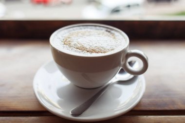Masada beyaz bardakta kapuçino kaşıklı kahve, kahve molası konsepti yüksek kaliteli fotoğraf