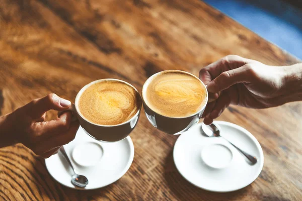 two cups of cappuccino coffee in friends hands, coffee break concept. High quality photo