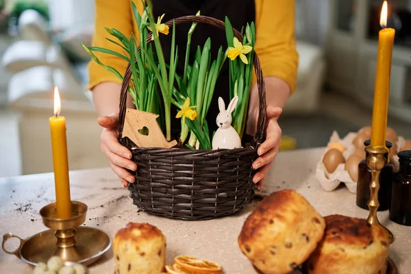 Easter cakes, candles on the background of basket with daffodils in women hands High quality photo