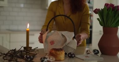 Paskalya sepetini kek, nakış işlemeli havlu ve masada lalelerle mutfak evinde yanan mum taşıyan bir kadın. Yüksek kalite fotoğraf