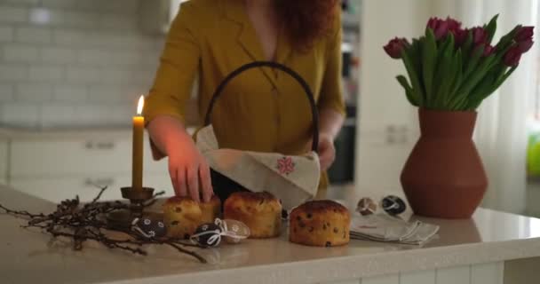 身穿黄色衣服的女人在厨房准备复活节篮子 绣花毛巾和点燃的蜡烛 桌上放着郁金香 高质量的照片 — 图库视频影像