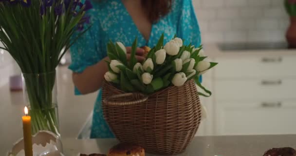 身穿蓝色衣服的白人妇女在自家厨房里准备复活节篮子 桌上放着传统的Kulich糕点和白色郁金香 高质量的4K视频镜头 — 图库视频影像