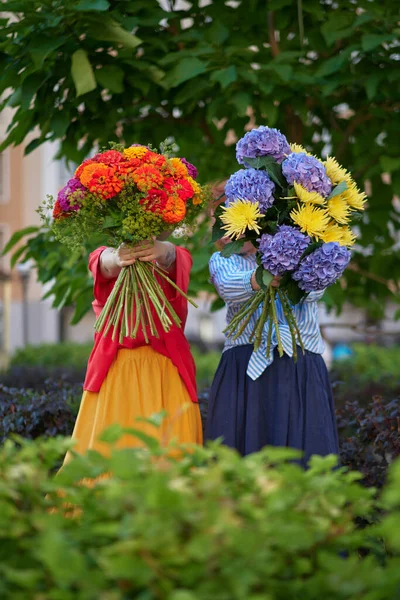 Dos Mujeres Sosteniendo Ramo Flores Azules Naranjas Amarillas Fondo Del —  Fotos de Stock