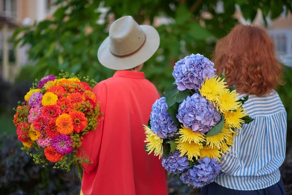 Dos Mujeres Sosteniendo Ramo Flores Azules Naranjas Amarillas Fondo Del —  Fotos de Stock