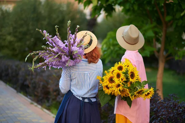 Dvě Ženy Držící Kytici Slunečnic Gladiolových Květin Pozadí Zelené Zahrady — Stock fotografie