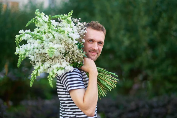 Man Met Een Bos Witte Bloemen Achtergrond Van Groene Tuin — Stockfoto