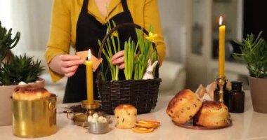 Easter cakes, candles on the background with woman growing daffodils in basket, at home. High quality photo