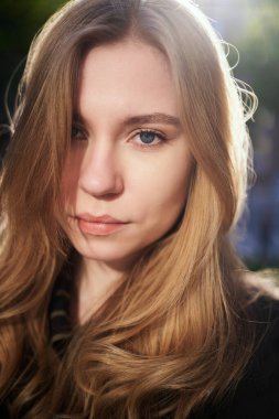 Güler yüzlü, doğal görünümlü, sarışın, gün batımında açık havada genç bir kız. Kameraya bakıyorum. Kaliteli fotoğraf.