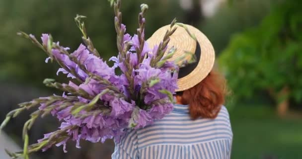 Red Haired Woman Blue Shirt Hat Walking Holding Bouquet Purple — Stock Video