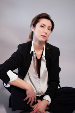 Siyah ceketli iş kadını izole edilmiş arka planda poz veriyor. Siyah takım elbiseli, ciddi suratlı, kameraya bakan neşeli bir menajer kadın. Yüksek kaliteli dikey fotoğraf