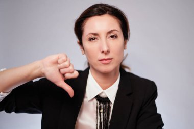 Siyah ceketli ciddi bir iş kadını izole edilmiş arka planda negatif bir hareketle poz veriyor. Koyu takım elbiseli neşeli yönetici kadın kameraya bakıyor. Yüksek kalite fotoğraf