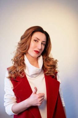Baş parmak hareketi yapıyor. Şık bordo takım elbiseli, dalgalı saçlı, kahverengi gözlü, beyaz tenli, güzel bir kadının stüdyo portresi. Yüksek kaliteli dikey fotoğraf