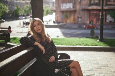 Yakından bakınca siyah çizgili elbiseli güzel sarışın beyaz kız dışarıda poz veriyor. Şık ve zarif bir kadının moda portresi. Yüksek kaliteli resim