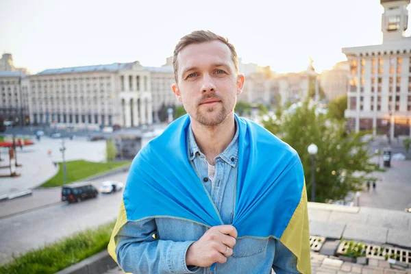 白种人男性穿着牛仔衬衫 上面覆盖着乌克兰国旗 与城市景观相抗衡 一个拿着乌克兰国旗的爱国者的画像 日落时间 自由概念 高质量的照片 — 图库照片