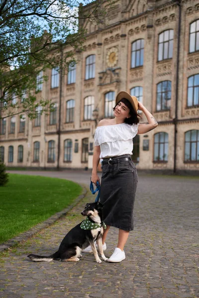 Güzel genç kadın ve köpek eski şehir manzarasında oturmuş kameraya gülümsüyor. Gülümsüyor ve köpeğe sarılıyor. Eski şehir manzarası. Yüksek kalite fotoğraf