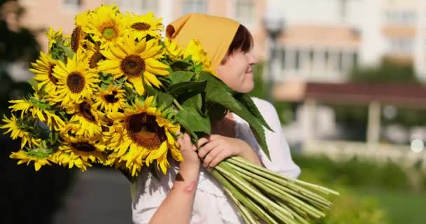 笑顔の女性の屋外の手の中に黄色のひまわりの花束 愛と愛国的な贈り物 母の日 ウクライナへの支援 独立記念日 高品質4Kビデオ映像 — ストック動画
