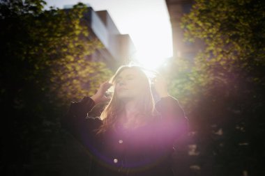 Zarif, zarif, siyah ceketli, saçları düzelten beyaz bir kız. Şık ve zarif bir hanımın moda portresi. Şehirli arka planı ve parlak ışıkları var. Yüksek kaliteli resim