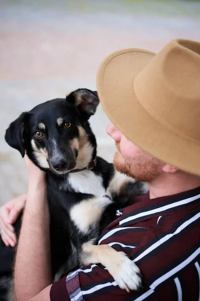Şapkalı Genç Adam Kurtarılmış Köpeğine Sarılıyor Dışarıdaki Kameraya Bakıyor Barınaktaki — Stok fotoğraf