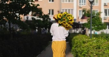 Beyaz kadın elinde ayçiçeği buketiyle kameradan çıkıyor. Vatansever hediye, sevgi ve minnettarlık. Anneler Günü. Ukrayna 'ya destek. Bağımsızlık Günü. Yüksek kalite 4k video