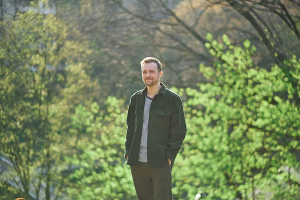 Νεαρός Άνδρας Χαμογελά Σίγουρος Στέκεται Στο Πάρκο Στο Φως Του — Φωτογραφία Αρχείου