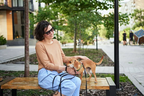 Şehirde Oturan Sarılan Gülümseyen Bir Köpeği Olan Genç Bir Kadın — Stok fotoğraf