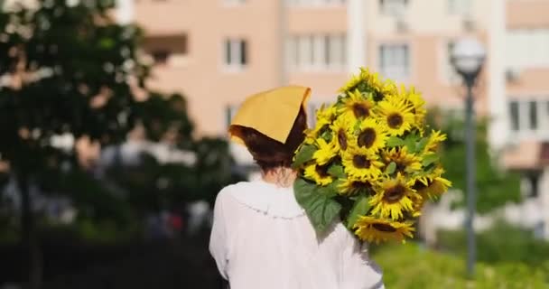 歩いている女性の手の中に黄色のひまわりの花束屋外 愛と愛国的な贈り物 母の日 ウクライナへの支援 独立記念日 高品質ビデオ4K — ストック動画
