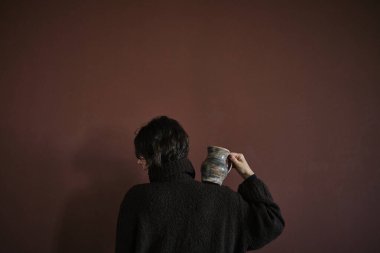 Önlüklü, el yapımı çömlek taşıyan genç bir kadın. Eski tip akrabalık kavramı. Gösterişsiz kusurlu fotoğraf. Minimalizm Yüksek kalite fotoğraf