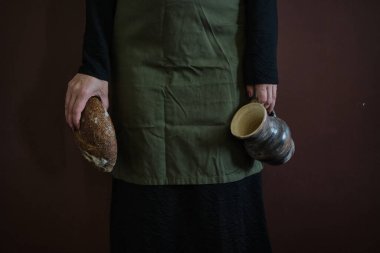 Önlüklü genç bir kadın elinde ekmek ve çömlekçilik, klasik akrabalık kavramı. Gösterişsiz kusurlu fotoğraf. Yüksek kalite fotoğraf